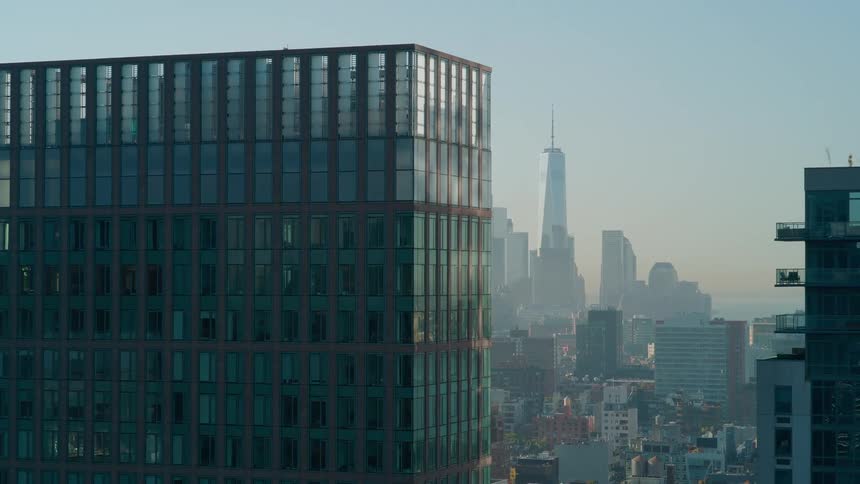 Glass building in the foreground with skyscrapers in the background of the city