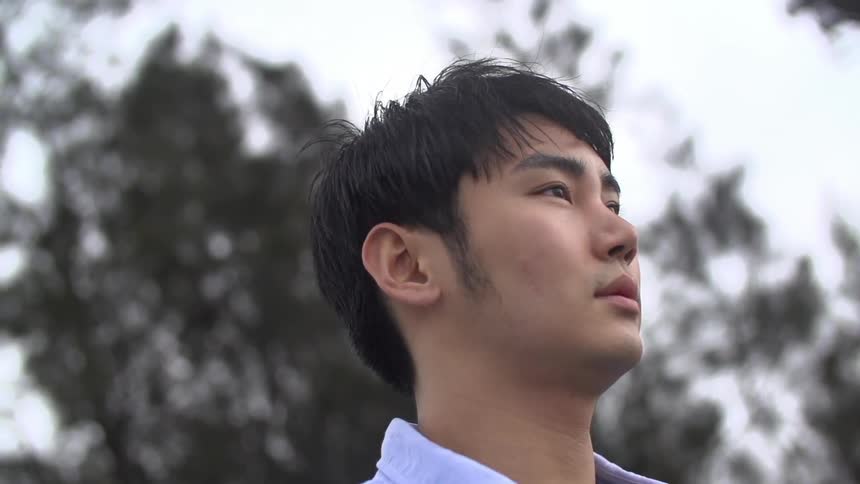 Tight shot of a young asian man gazing into the distance