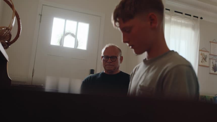 The boy is having a piano lesson at home