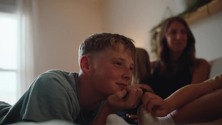 Boy with hand on chin and breathing happily with his family around