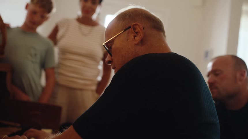 Man playing piano with people watching around
