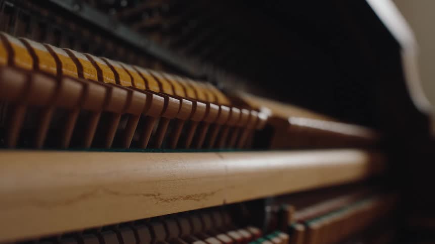 A closeup shot shows the wooden hammers and inner mechanics of the piano