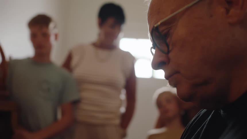A teenage boy a young girl and their grandmother pay attention as the grandfather focuses on something