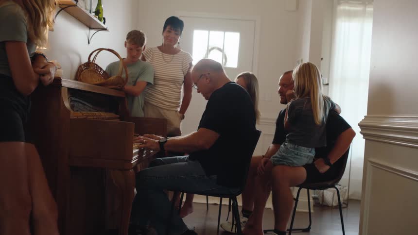Family watching a man playing the piano