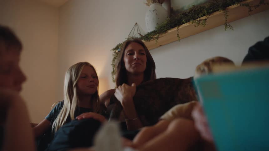 Woman pulls a cat over her lap while sitting with her family on a couch in the living room
