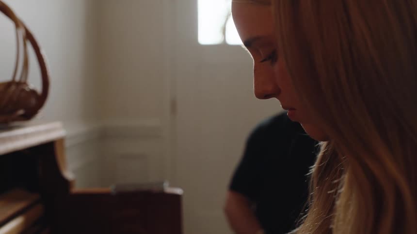 The teacher watches as the student practices piano