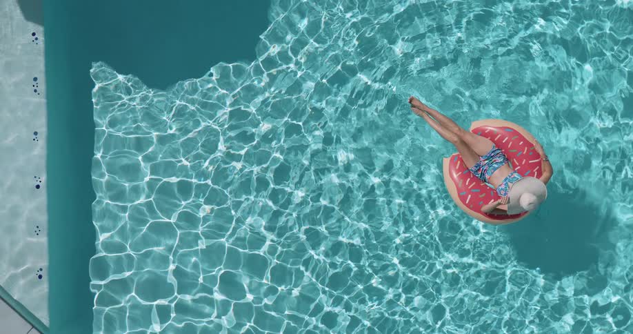 Woman lies on a ring float while relaxing in a swimming pool on a summer day