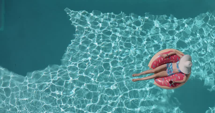The woman kicks her feet while floating in the pool