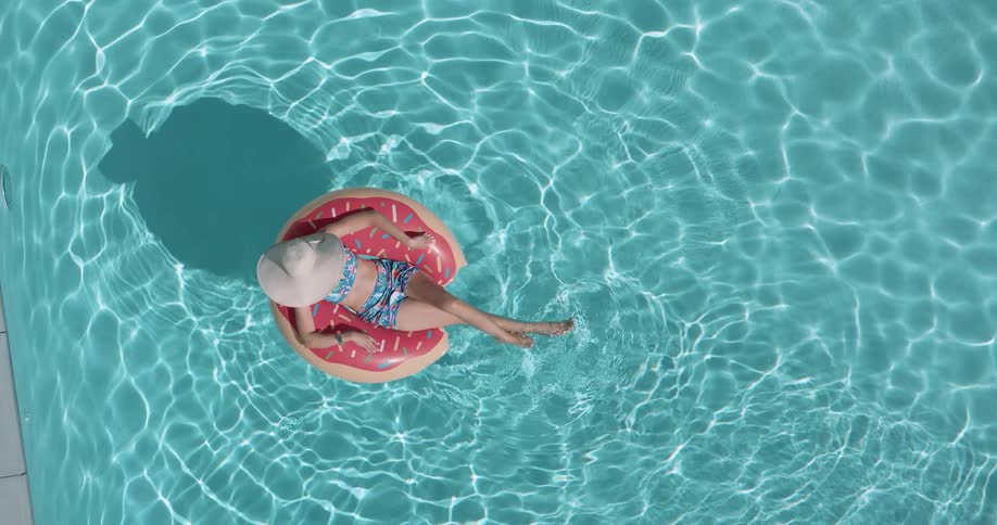 Top view of a woman relaxing on a float in the pool
