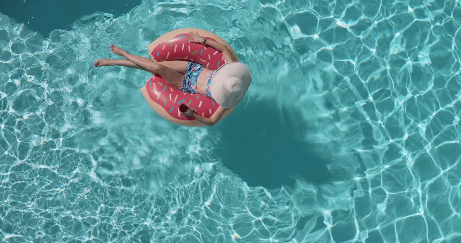 Woman in a hat relaxing on a float in the pool