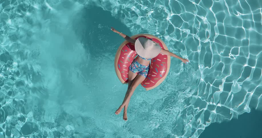 Woman in a hat lying on a float in the pool