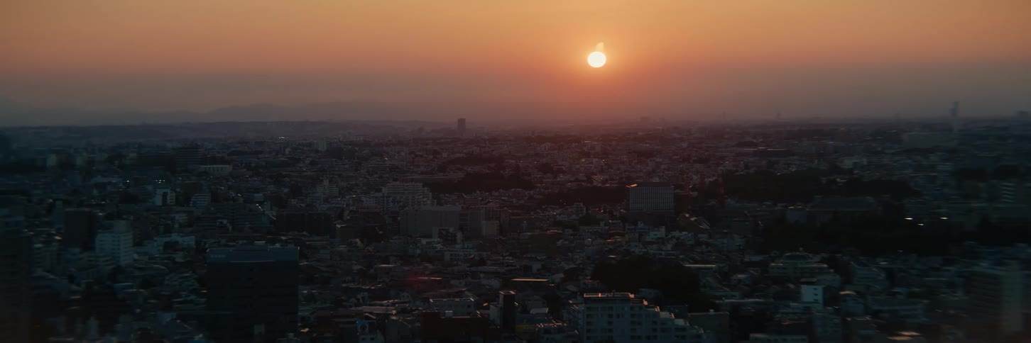 Sun flares in a red sky over a sprawling city