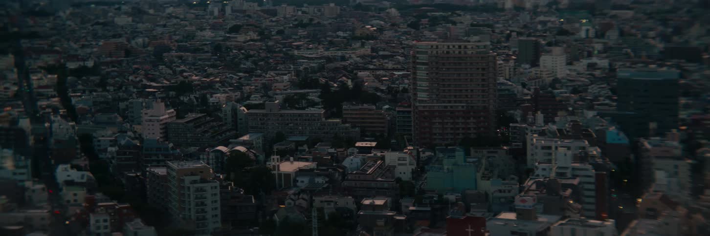 A highangle static shot looks out over a vast and densely packed major city as the low light of dusk settles over the buildings