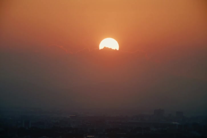 Reddish sun rising on the horizon over the city