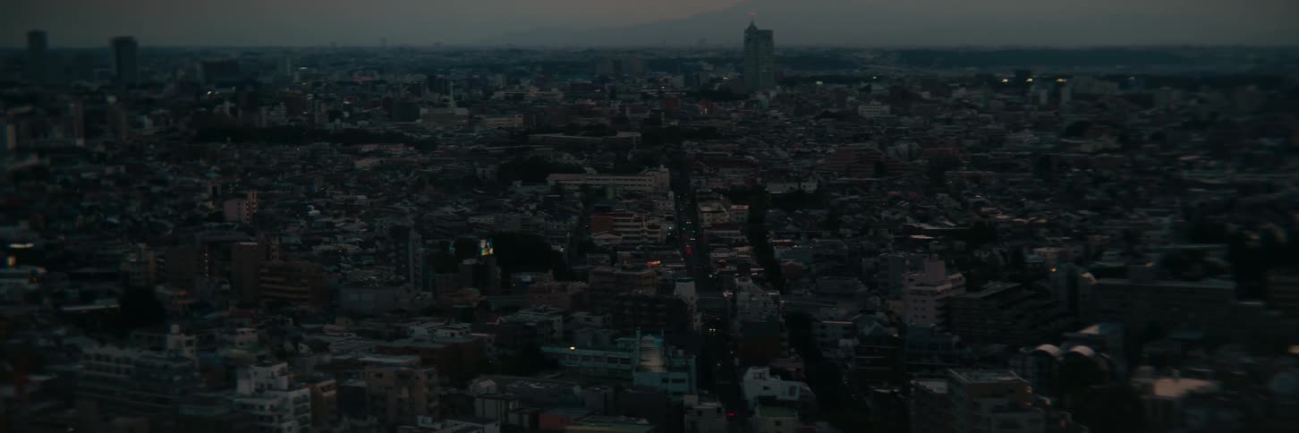 Few building lights shine in a sprawling city during the evening