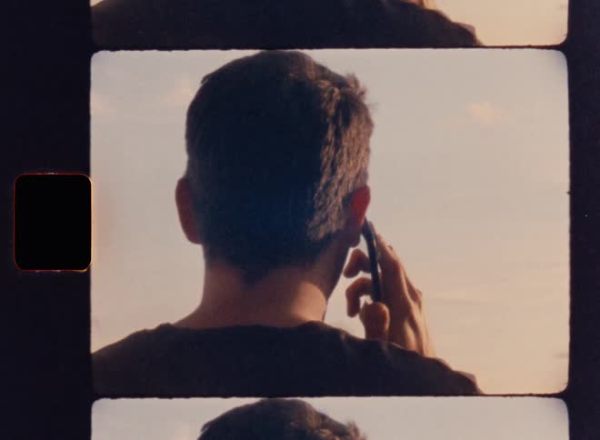 Man standing on a high area overlooking the neighborhood talks on a smartphone