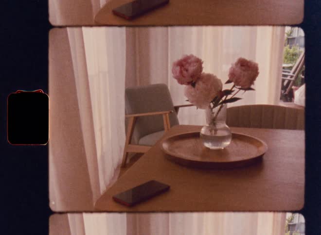 The cell phone is on the table near the flowers