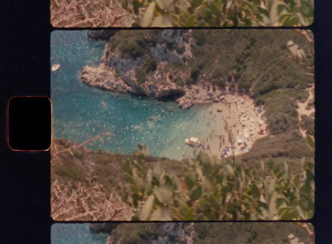 Cinematic Super 8mm aerial view of a crowded turquoise cove beach with swimmers, umbrellas and a small boat, framed by rocky cliffs, dense green vegetation and vintage film strip borders, captured with subtle handheld camera movement