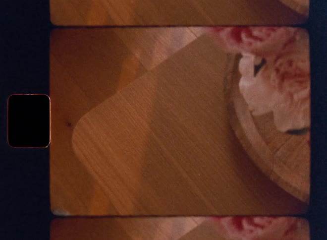 Person picking up and placing a smartphone on top of a wooden surface