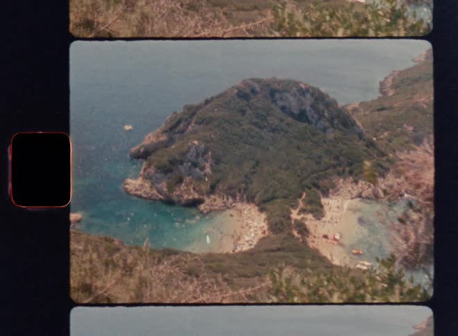 Cinematic Super 8mm pan revealing a hidden island with turquoise coves and lush green cliffs, captured as the camera rises from behind a bush to unveil the scenic coastline and crystal-clear Mediterranean waters in vintage analog style