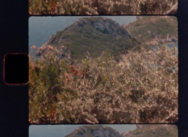 Cinematic Super 8mm reveal shot: camera rises from behind coastal bushes to unveil a lush green island surrounded by turquoise sea, capturing a nostalgic vintage travel aesthetic with warm film grain and scenic Mediterranean landscape