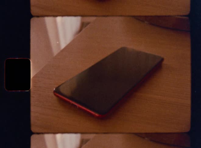 A smartphone with a red casing lies on a wooden surface