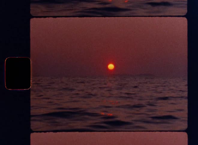 Cinematic Super 8mm shot of a calm ocean at sunset with a glowing red sun on the horizon and gentle waves in motion, captured with vintage film grain, nostalgic color tones, and authentic analog frame borders