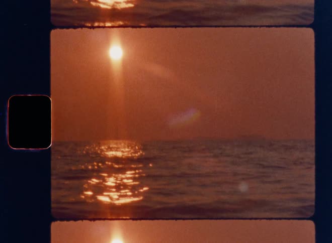 Cinematic Super 8mm sunset over calm ocean waters with glowing golden light path, gentle waves, warm orange sky, natural lens flares, and authentic vintage film grain captured in a nostalgic analog film strip frame