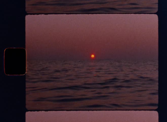 Cinematic shot of a glowing sun setting over calm ocean waves under a hazy pink sky, captured with nostalgic film grain, warm color shifts, and authentic analog imperfections on Super 8mm film