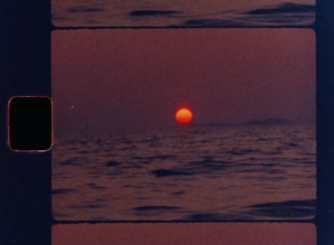 Cinematic Super 8mm sunset over dark rolling ocean waves, vivid orange sun dipping below the horizon under a deep red sky, framed with vintage film strip borders and textured grain for a nostalgic analog aesthetic