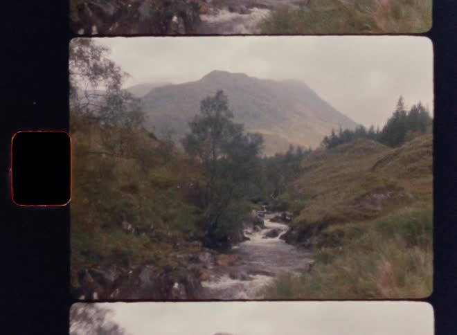 A river flowing through a green mountainous landscape under a cloudy sky