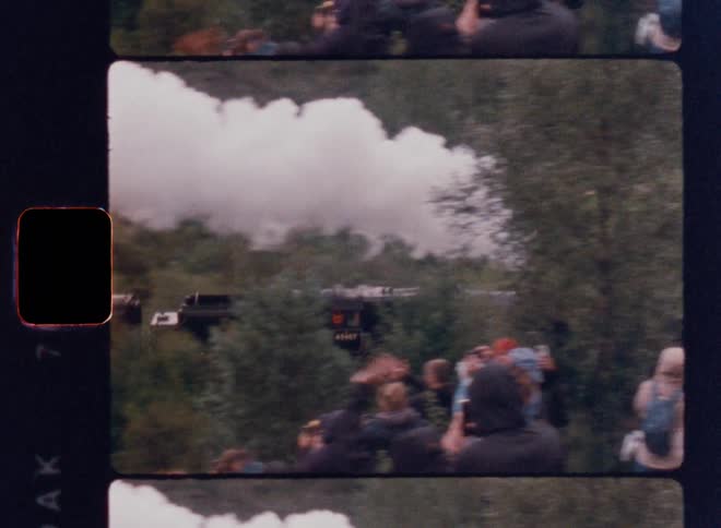 A crowd waves at a steam train