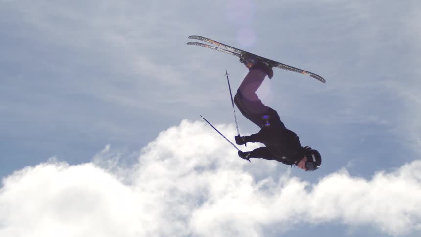The man does a flip in the air on snow skiis