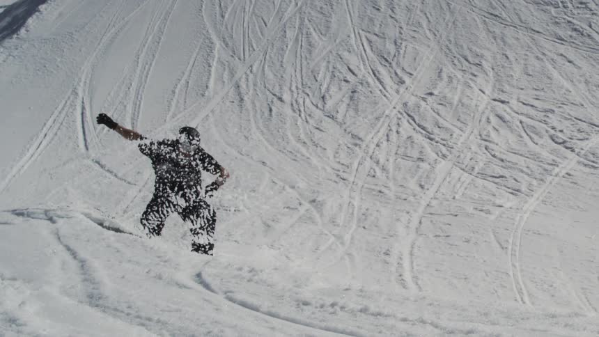 The video shows two shots of a snowboarder in midair on a snowy mountain the first shot is a closeup against a bright blue sky while the second pulls back to show the surrounding ski lifts and the words filmsupply as a watermark