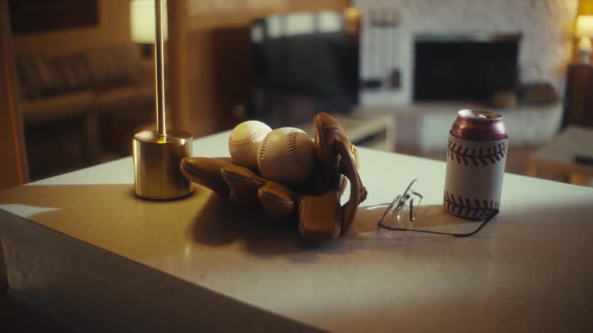 Baseballs and a mitt are on the counter with a drink