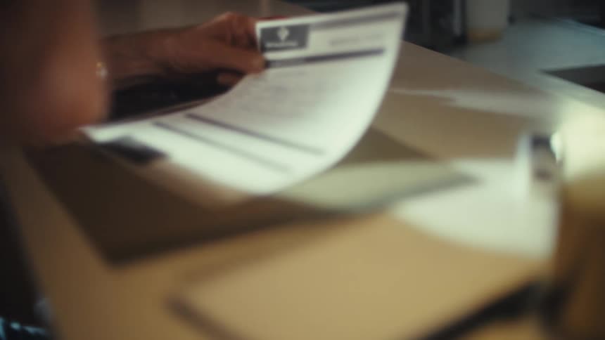 Elderly man fills out a medical form with a pen on the table