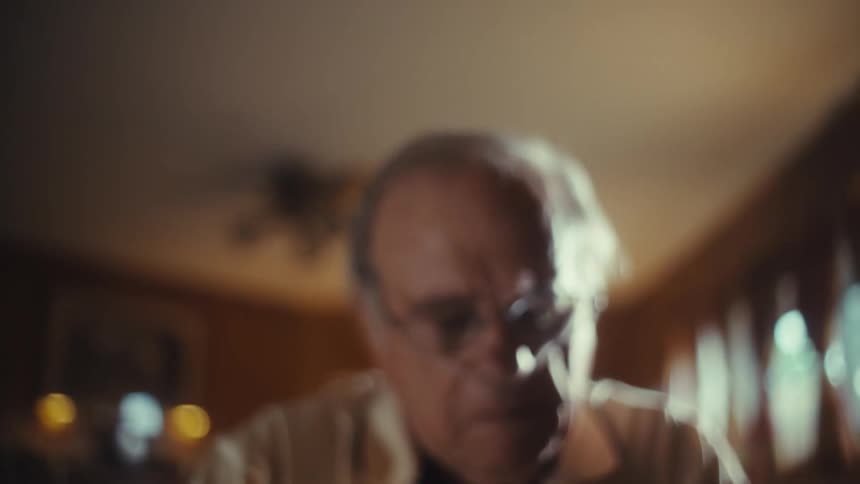 Elderly mans hand using a fingertip oximeter over medical scans