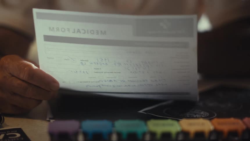 Hands holding a medical form over a table with a colorful pill organizer