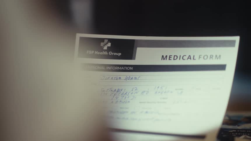 Closeup of hands holding a filled medical form indoors