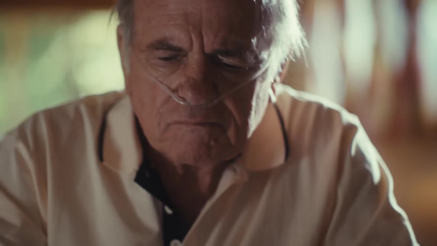 Elderly man reading a medical form next to a pill organizer