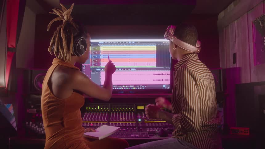Two women analyze audio tracks in a studio in front of the editing screen