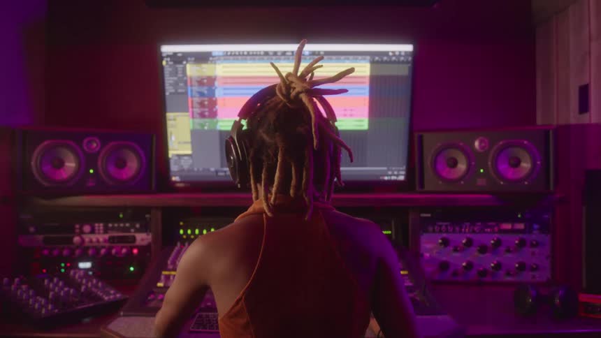 The woman is bobbing her head while making music in the studio