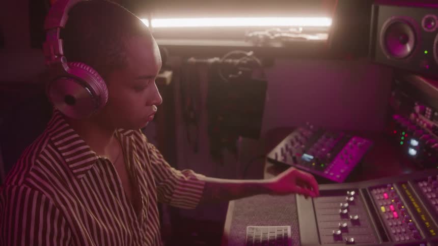 Woman in headphones working on a mixer in a music studio
