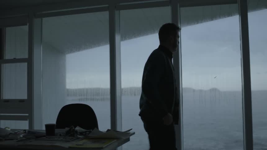 Man gets up from office desk and looks out the window