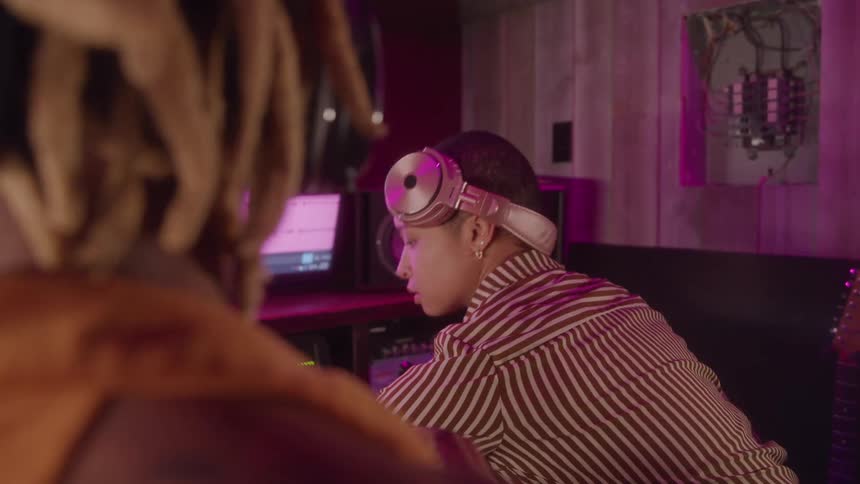 Woman with headphones resting on her head works in a recording studio