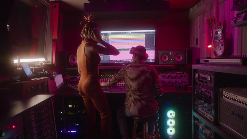Two women work in a recording studio adjusting details in the music production