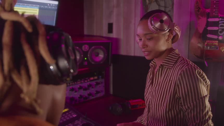 Two women with headphones singing in a studio