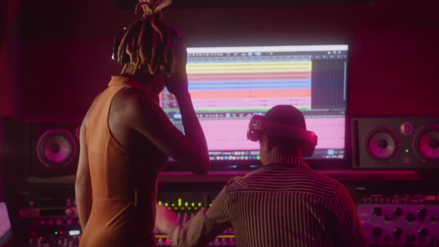 Two women working in a studio in front of a computer with mixing