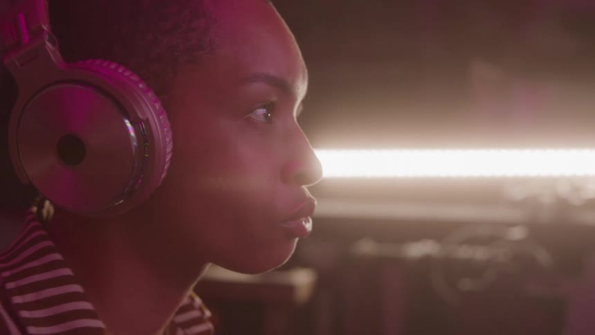 Woman working indoors focuses while listening to music on headphones
