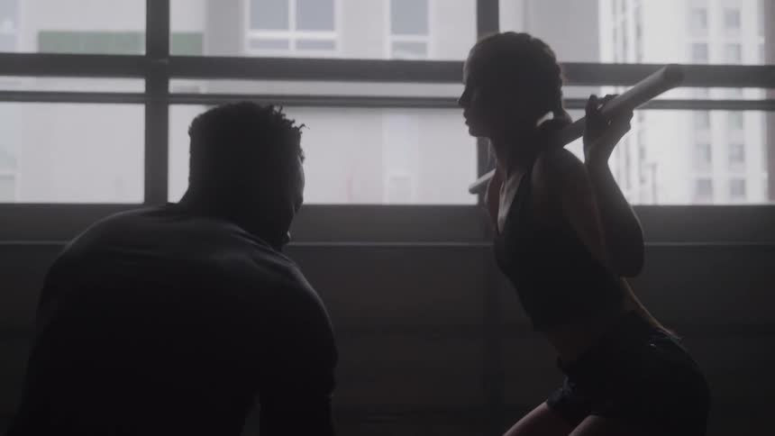 Trainer assists athlete during a squat exercise with a barbell